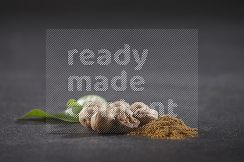 Nutmeg seeds with nutmeg powder beside it on a black flooring in different angles