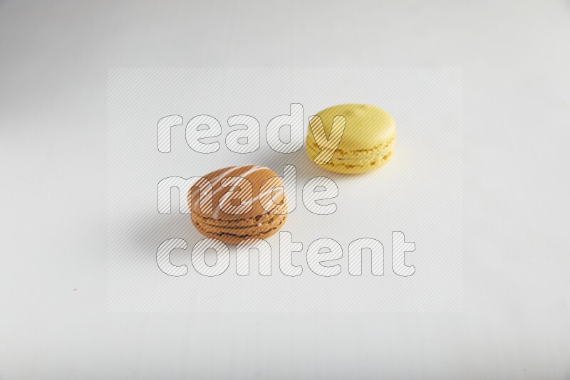 45º Shot of of two assorted Brown Irish Cream, and Yellow Lemon macarons on white background