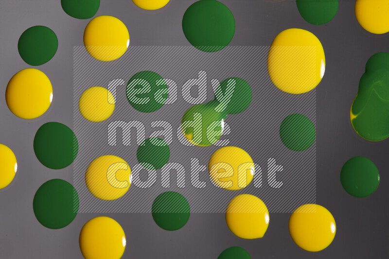 Close-ups of abstract yellow and green paint droplets on the surface