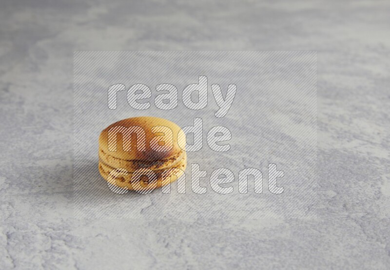 45º Shot of Yellow Crème Brulée macaron on white marble