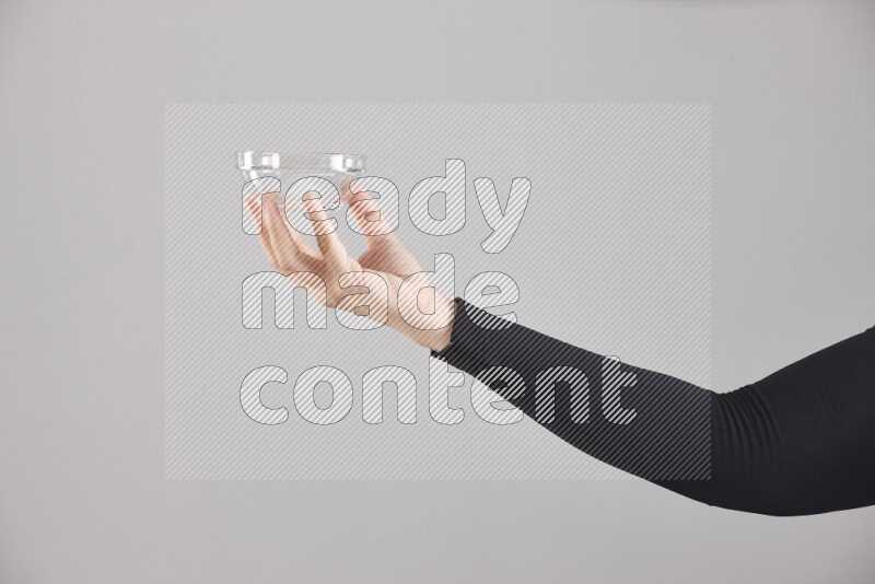 A woman in black abaya holding different glassware in different positions