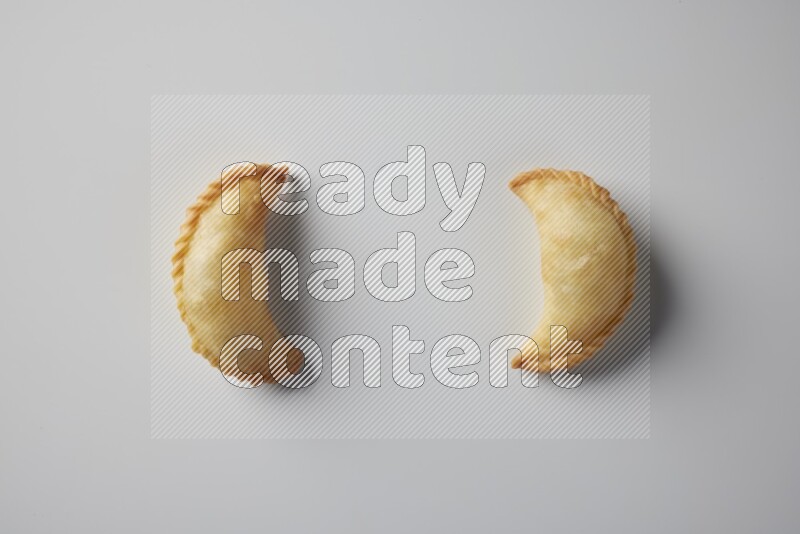 Two fried sambosa from a top angle on a white background