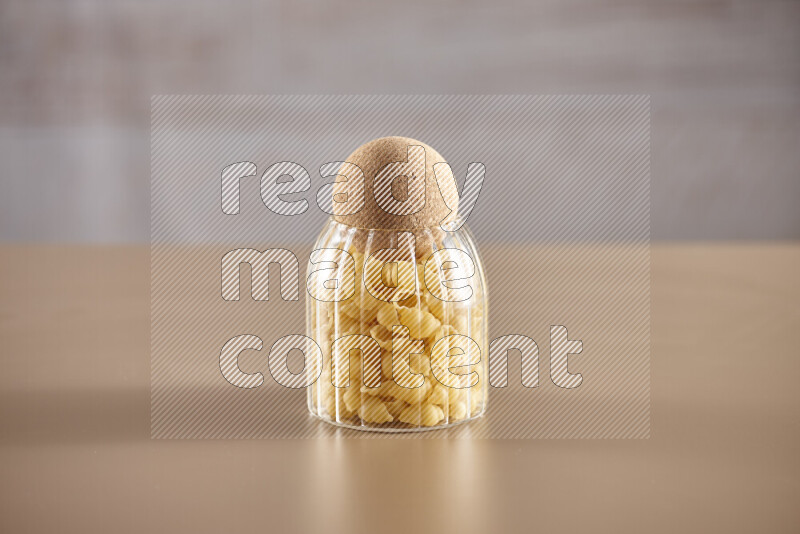 Raw pasta in glass jars on beige background