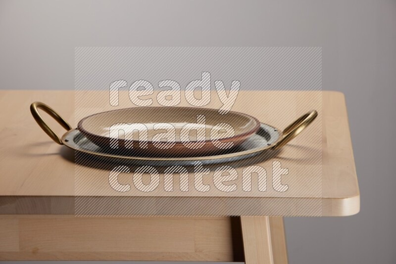 multicolored plate placed on a rounded stainless steel tray with golden handels on the edge of wooden table