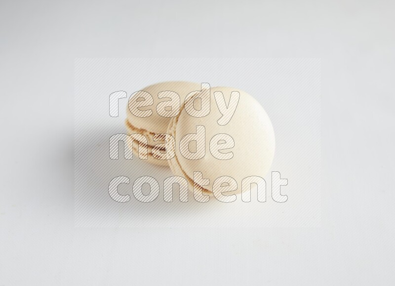 45º Shot of two White Caramel fleur de sel macarons on white background
