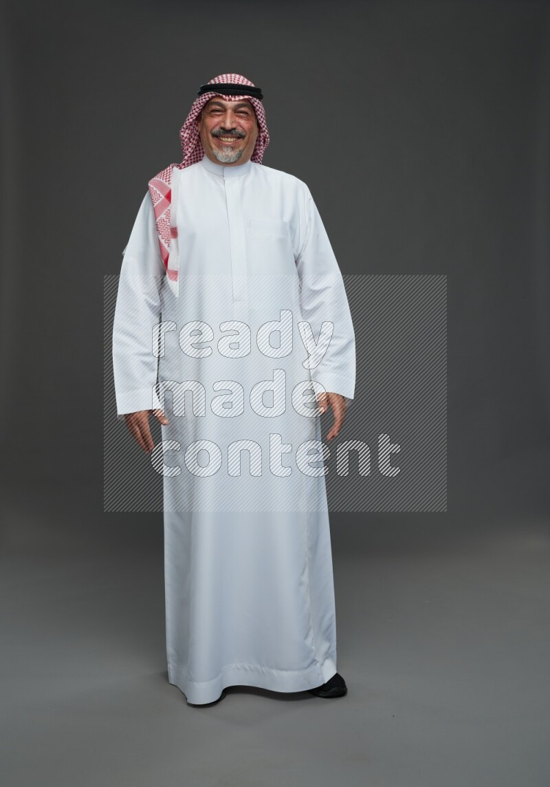 Saudi man with shomag Standing Interacting with the camera on gray background