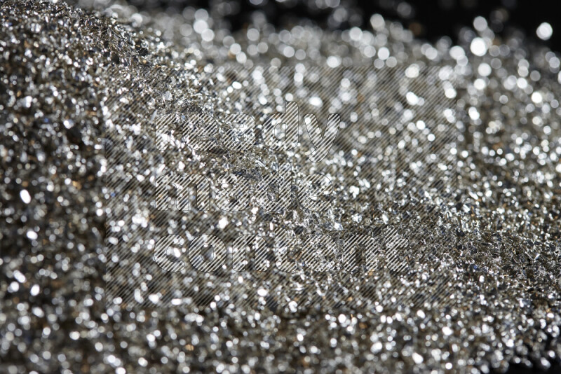 Silver shimmering fragments of glass scattered on a black background