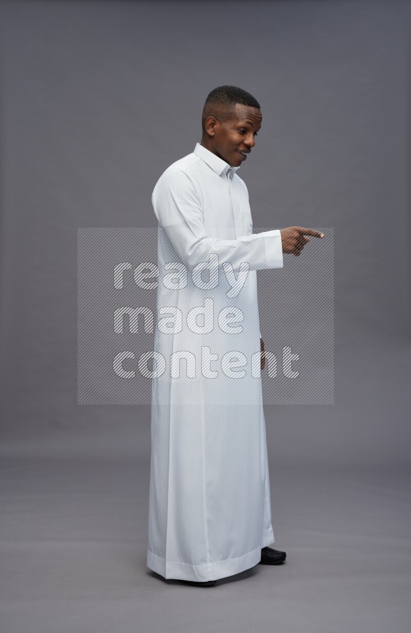 Saudi man wearing thob standing interacting with the camera on gray background