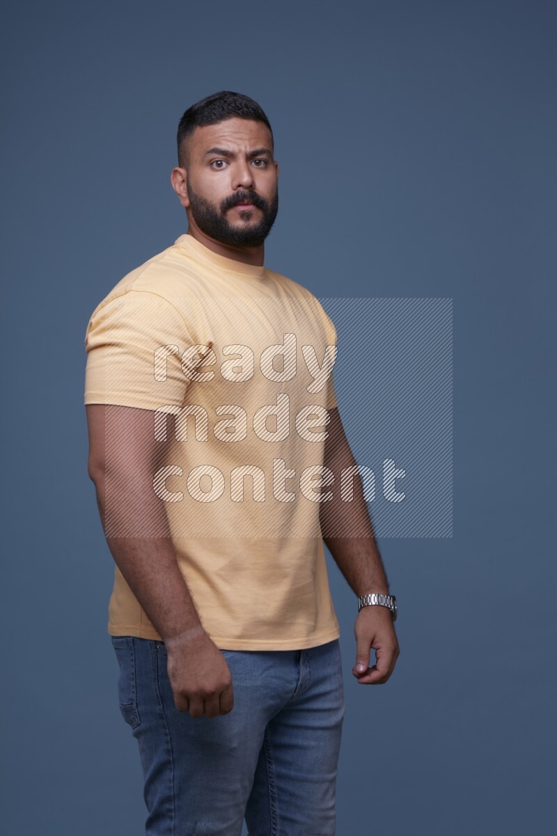 رجل يرتدي قميص اصفر بأكمام قصيرة وبنطال جينز ازرق يقف بأوضاع مختلفة