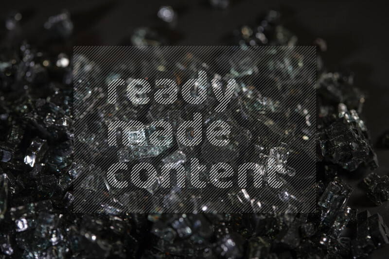 Transparent black fragments of glass scattered on a black background