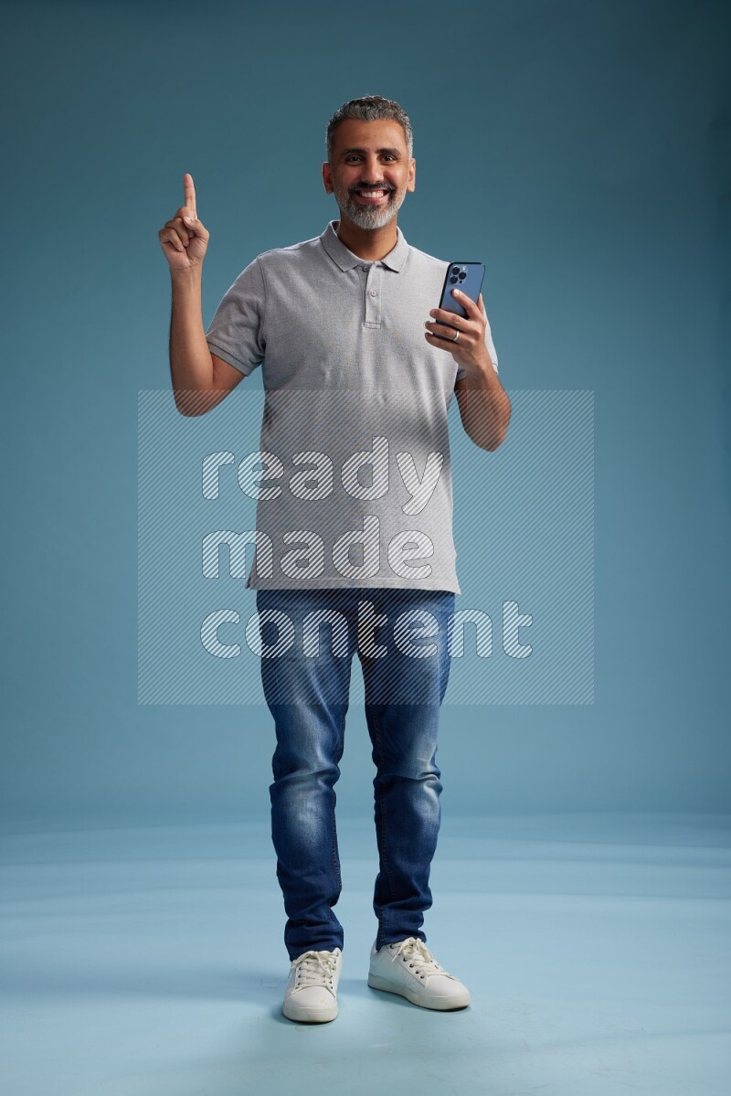 Man Standing texting on phone on blue background