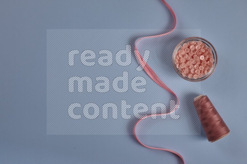 A pink collection of sewing and tailoring tools arranged on a blue background