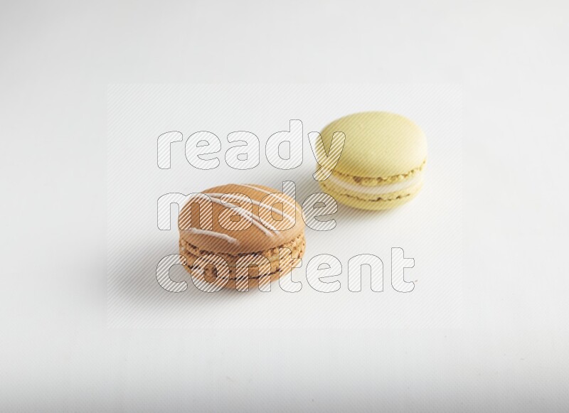 45º Shot of of two assorted Brown Irish Cream, and Yellow Lime macarons on white background