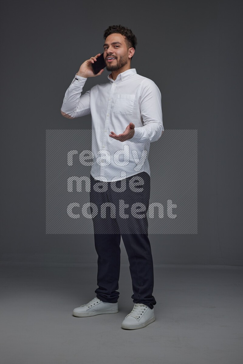 A man wearing smart casual talking in the phone eye level on a gray background