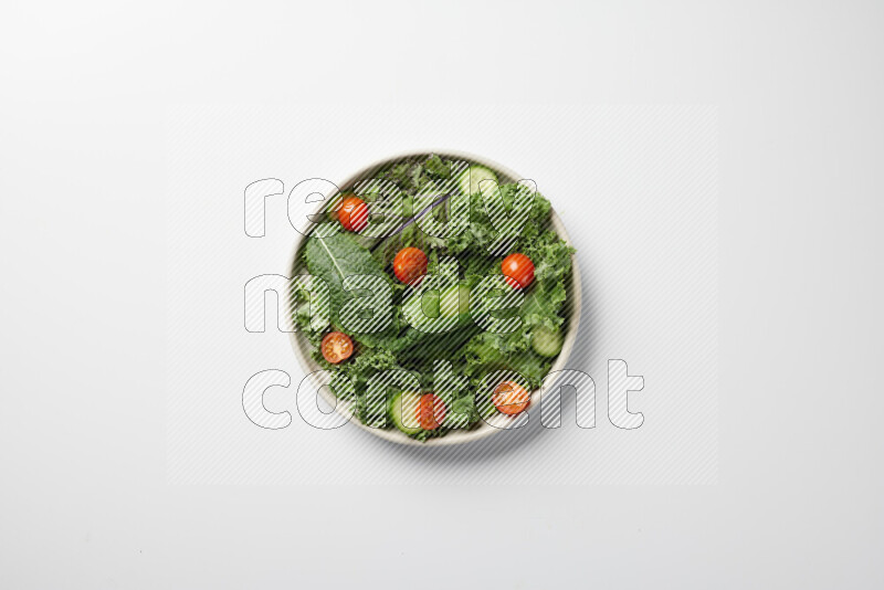A bowl of fresh vegetables salad with kale leaves, cherry tomatoes, sliced radishes and sliced cucumber on a white background