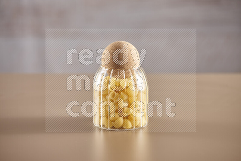 Raw pasta in glass jars on beige background