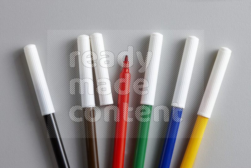An arrangement of coloring pens in different colors on grey background
