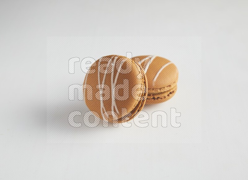 45º Shot of two Brown Irish Cream macarons on white background
