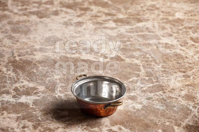 A small copper pot on beige marble background