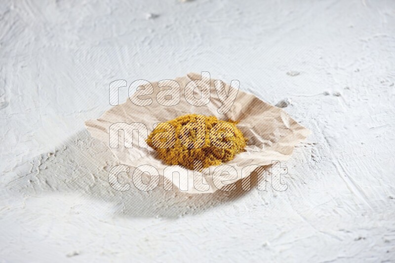Turmeric powder in a crumpled piece of paper on textured white flooring