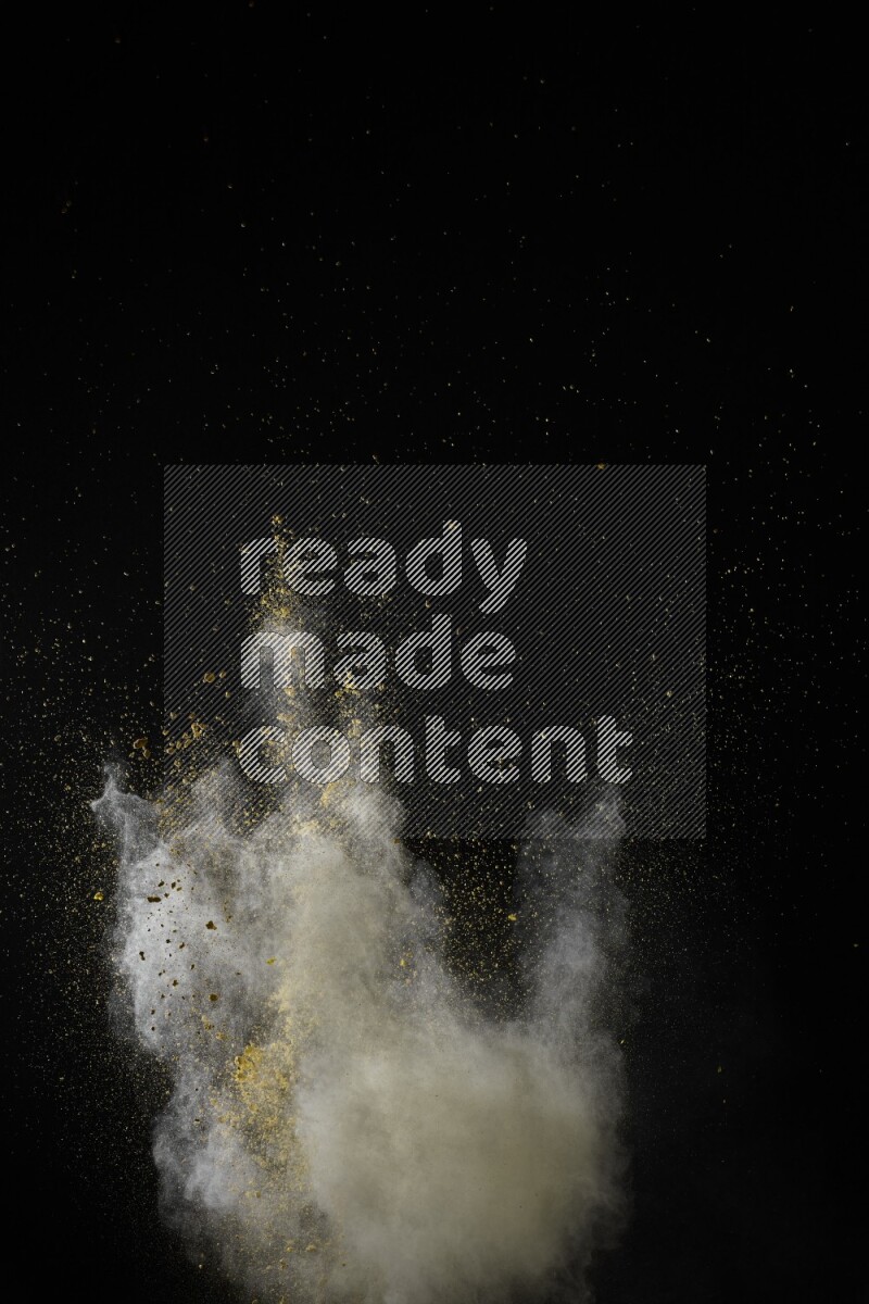 A side view of yellow powder explosion on black background