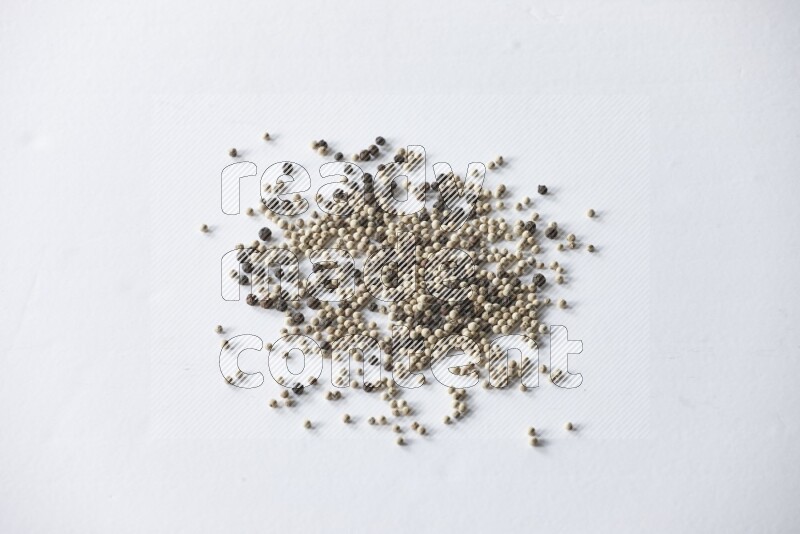 حبوب الفلفل المختلطة السوداء والبيضاء على أرضية بيضاء