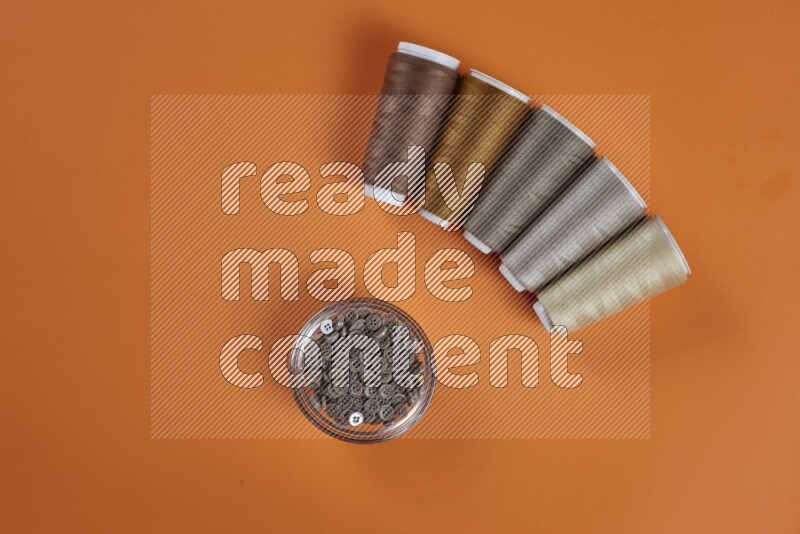 A brown collection of sewing and tailoring tools arranged on a orange background