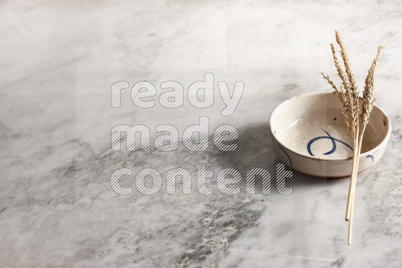 Wheat stalks on multicolored pottery bowl on grey marble background