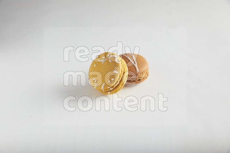 45º Shot of of two assorted Brown Irish Cream, and Yellow Piña Colada macarons on white background