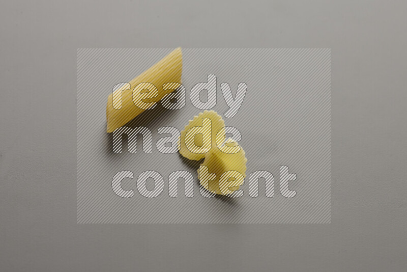 Penne pasta with other types of pasta on grey background