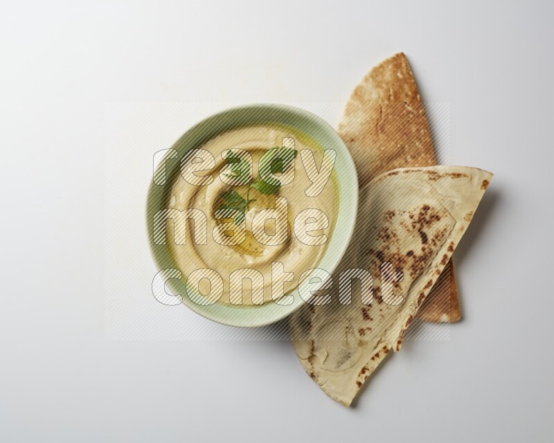 Hummus in a green plate garnished with parsley on a white background