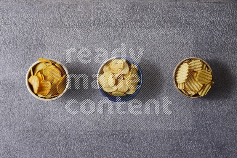 Assorted snacks in pottery bowls on grey background