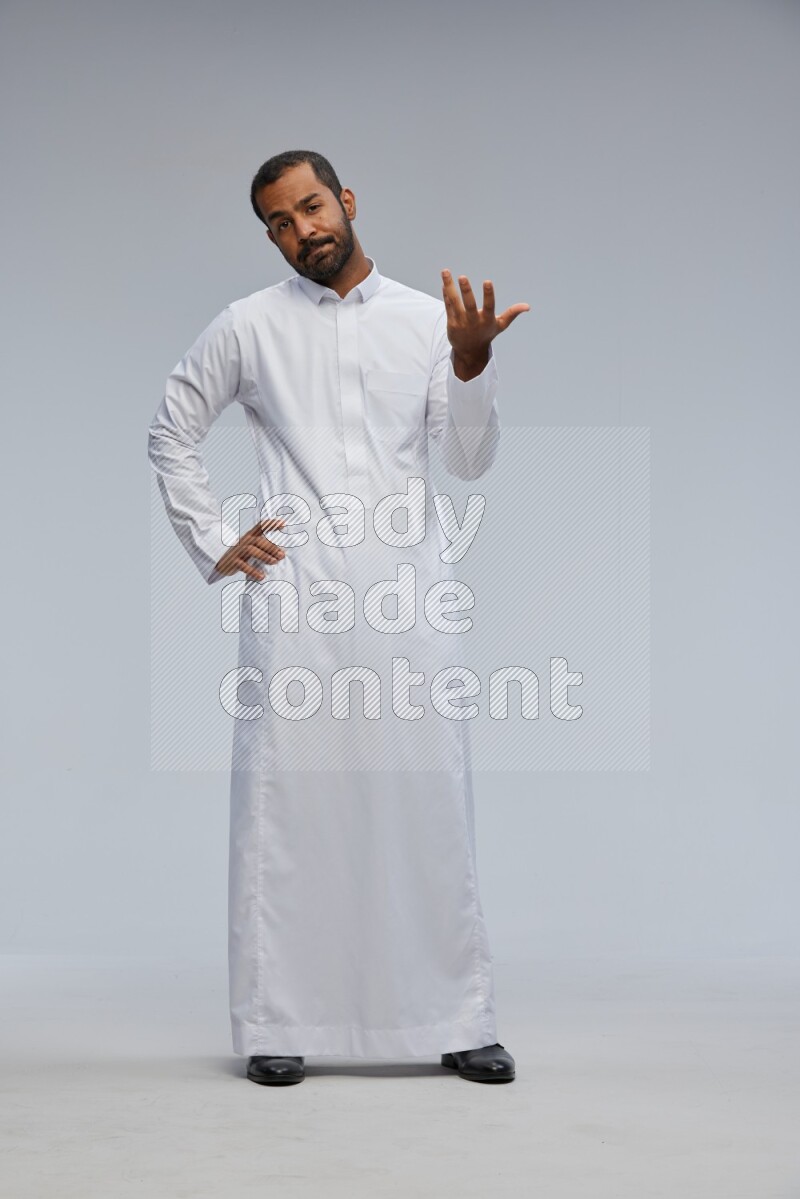 Saudi man Wearing Thob standing interacting with the camera on Gray background