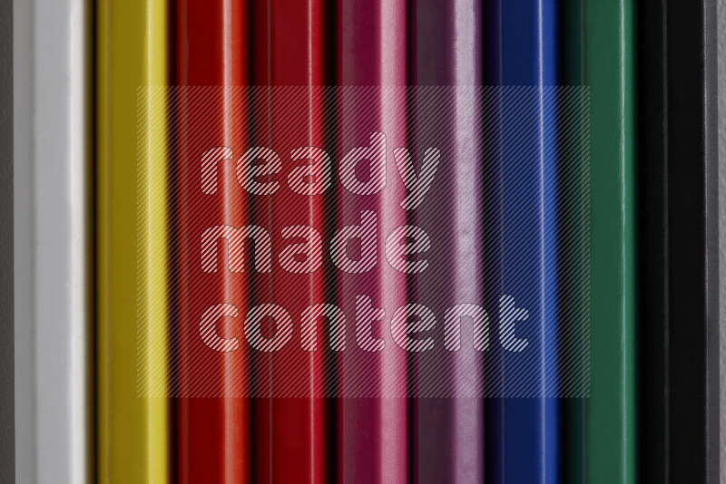 مجموعة من أقلام الرصاص الملونة مرتبة لتعرض تدرجا من الألوان المختلفة علي خلفية رمادية