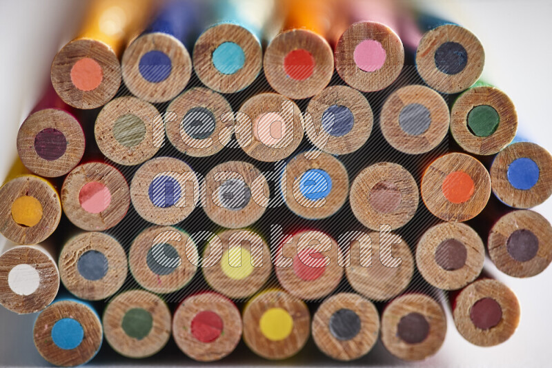 A close-up of the tips of colored pencils arranged in a bundle on white background