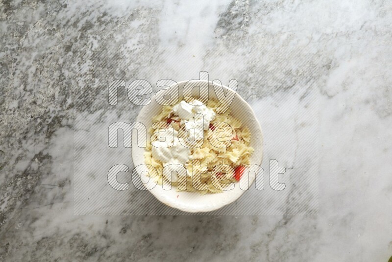 White bowl full of pasta on grey marble background