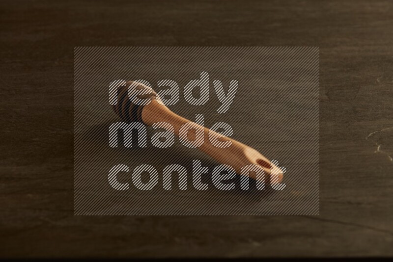 Wooden honey dipper on black slate background
