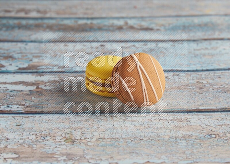 45º Shot of of two assorted Brown Irish Cream, and Yellow Lemon macarons on light blue background