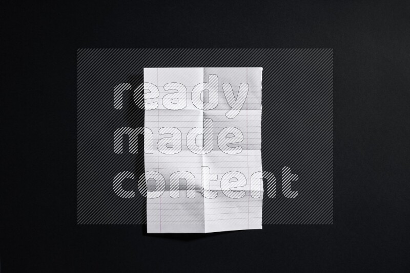 Folded notebook sheet on black background