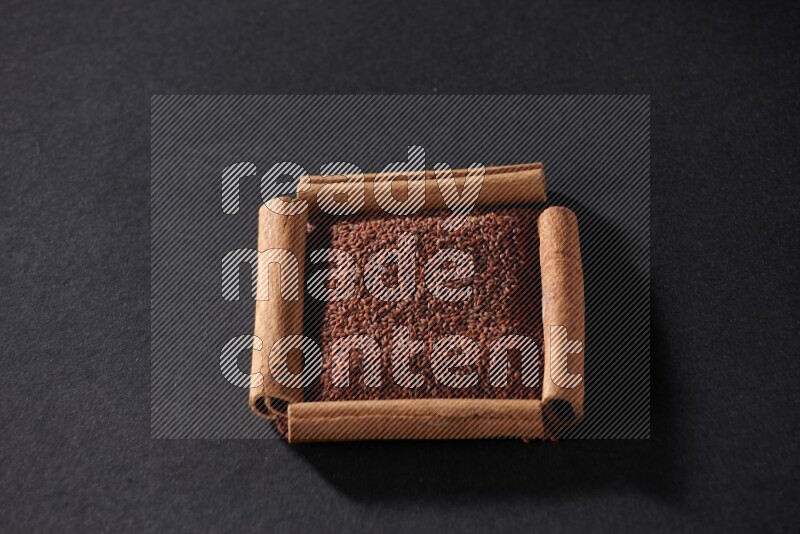 A single square of cinnamon sticks full of garden cress on black flooring