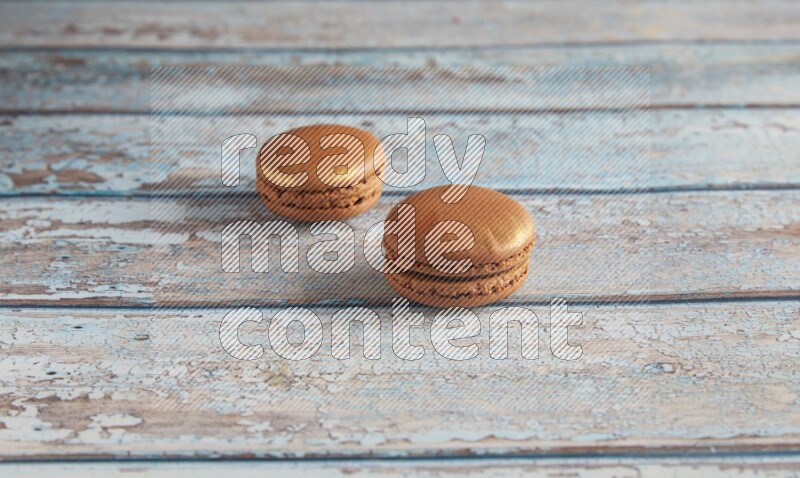 45º Shot of two Brown Coffee macarons on light blue wooden background