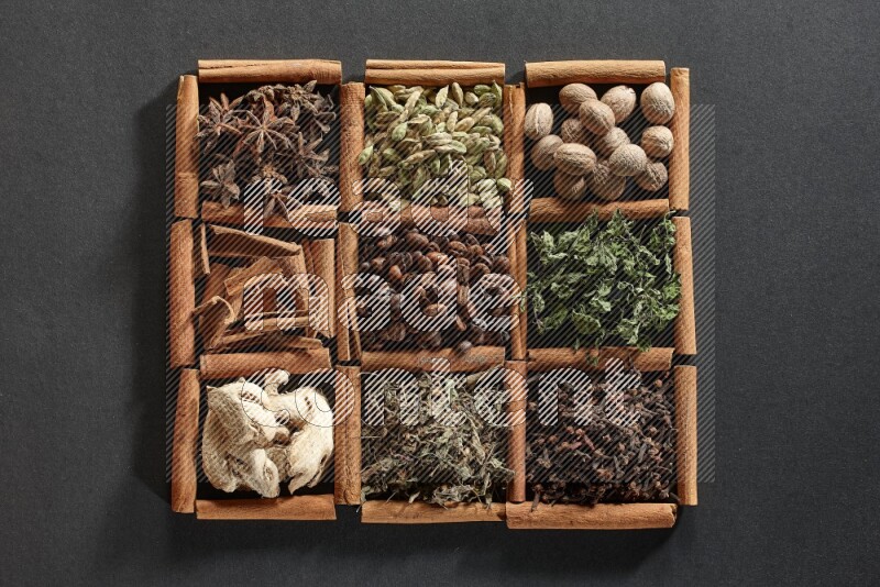 9 مربعات من أعواد القرفة ممتلئة بحبوب القهوة في المنتصف محاطة بجوزة الطيب والنعناع المجفف والقرنفل والريحان المجفف والزنجبيل المجفف والقرفة واليانسون والهيل على أرضية سوداء