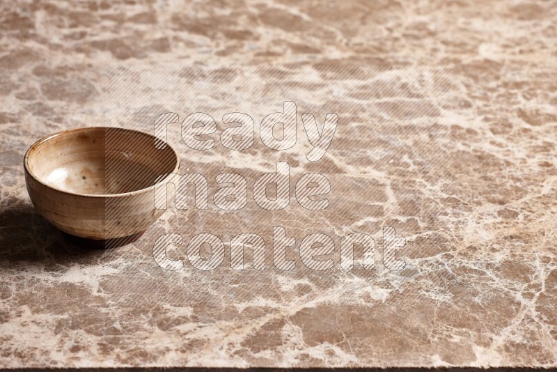 A beige pottery bowl on beige marble background