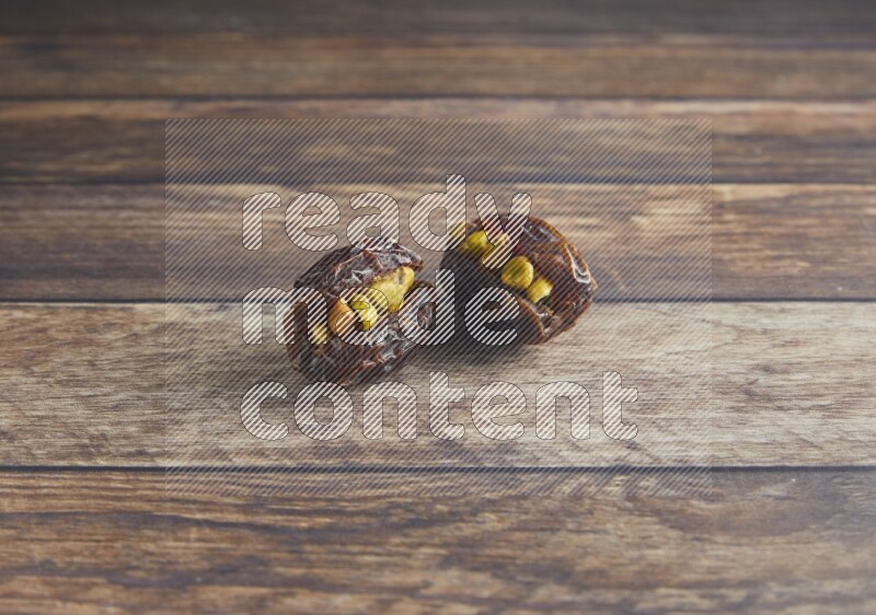 two pistachio stuffed madjoul date on a wooden background