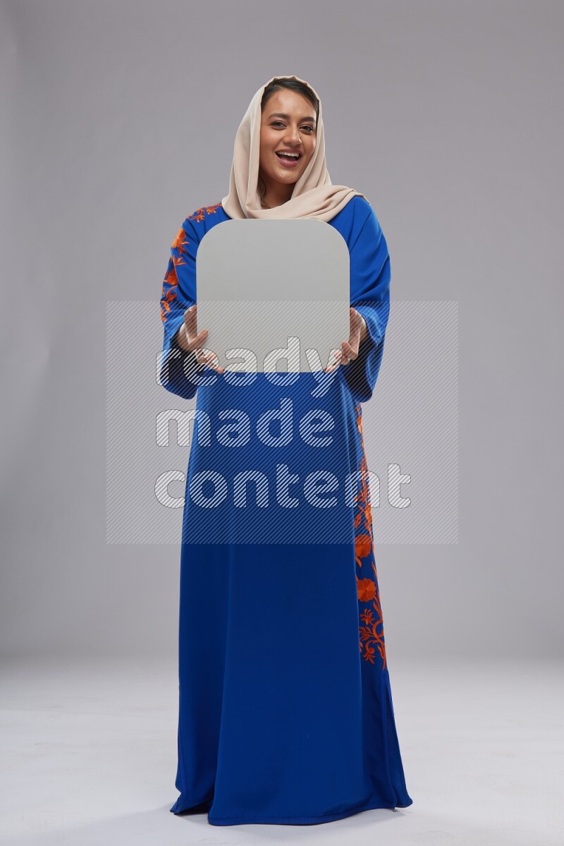 A Saudi woman standing wearing Jalabeya holding a social media sign