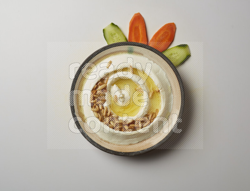 Lebnah garnished with pine nuts in a pottery plate on a white background