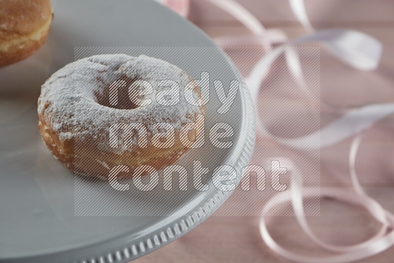Sugar dusted doughnut on pink wooden background