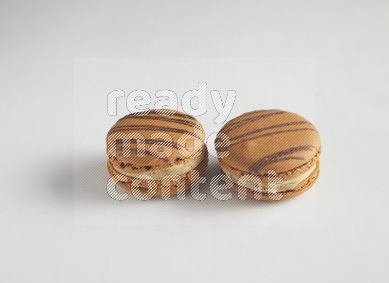 45º Shot of two light brown  Almond Cream macarons on white background