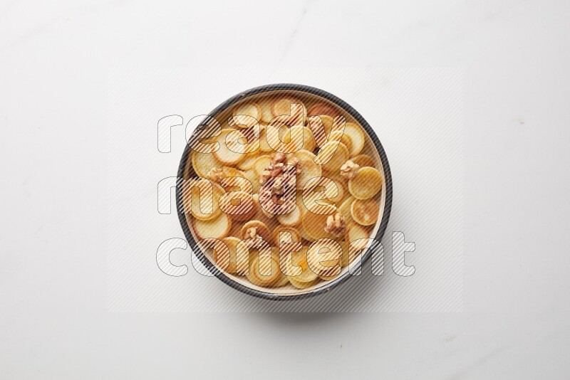 Top-view shot of walnut and apricot cereal pancakes in a round bowl on white background