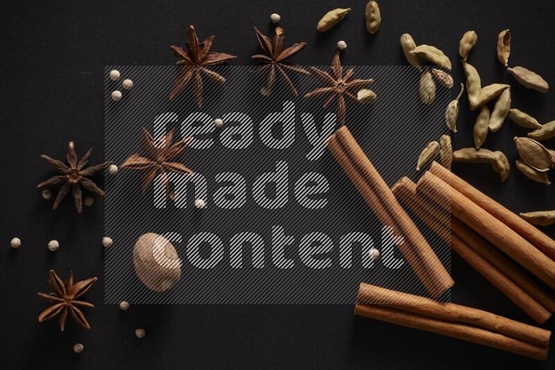Cinnamon sticks, cardamom, star anise, nutmeg and white peppers on a black background